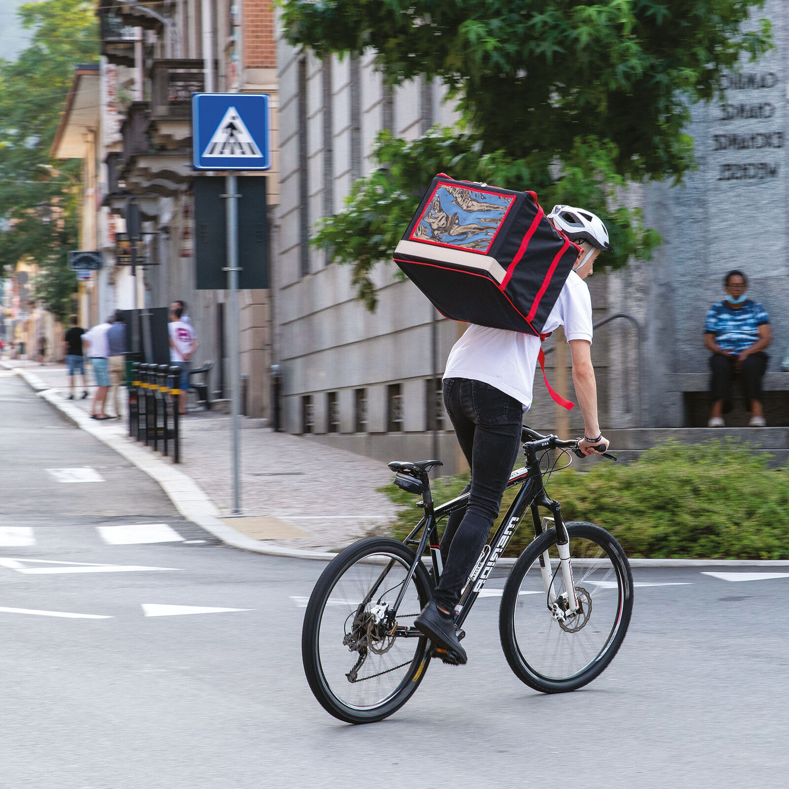 Nova Delivery futár kerékpáron, hátizsák-táskával, városi utcán